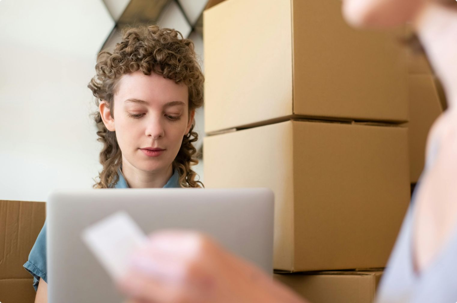 An online shop owner packing orders beside stacked boxes